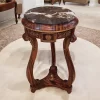 ترابيزة جانبية أنيقة مصنوعة من الرخام والخشب بتصميم كلاسيكي، تتميز بسطح رخامي أملس وأرجل خشبية منحوتة بدقة وزخارف نحاية على الحواف.