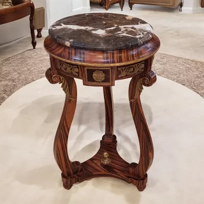 ترابيزة جانبية أنيقة مصنوعة من الرخام والخشب بتصميم كلاسيكي، تتميز بسطح رخامي أملس وأرجل خشبية منحوتة بدقة وزخارف نحاية على الحواف.