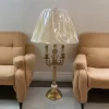 أباجورة معدنية راقية مصنوعة من مواد عالية الجودة يشكل الشمعدان باللون النحاسي وغطاء بليسيه بيج أنيق. مثالية لغرفة الصالون.