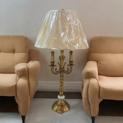 أباجورة معدنية راقية مصنوعة من مواد عالية الجودة يشكل الشمعدان باللون النحاسي وغطاء بليسيه بيج أنيق. مثالية لغرفة الصالون.