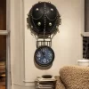 ساعة حائط معدنية بتصميم مستوحى من المناطيد الهوائية، تصميمها الفريد باللون الأسود يضفي عليها مظهرًا فاخرًا. هدية مثالية لمحبي السفر والمغامرة