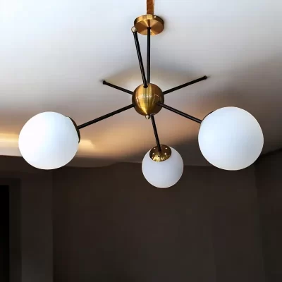 نجفة معدنية ذهبية مع كلوبات زجاجية بيضاء، تصميم أنيق وعصري لإضاءة المنزل.