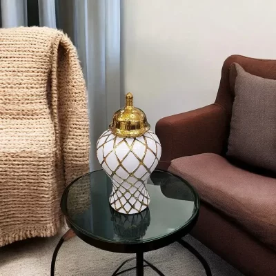 فازة زنجبيل فاخرة بتصميم شبكي ذهبي وأبيض على طاولة، مثالية لإضافة لمسة من الأناقة والفخامة إلى غرفة المعيشة.