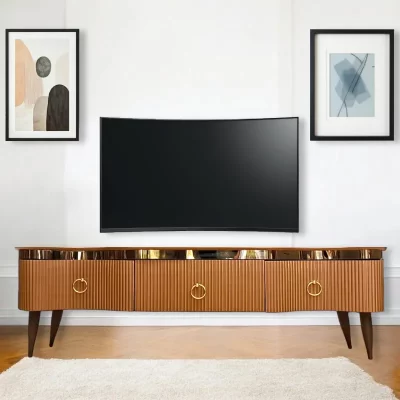 ترابيزة تليفزيون ذات ثلاثة أدراج، بتصميم كلاسيكي عصري. تتميز بمزيج جذاب بين اللون الذهبي فى الجزء السفلي واللون الخشبي الدافئ في السطح العلوي. لها ثلاثة أدراج كبيرة الحجم، وأرجل خشبية رفيعة وطويلة. مثالية لغرفة المعيشة وغرفة النوم.