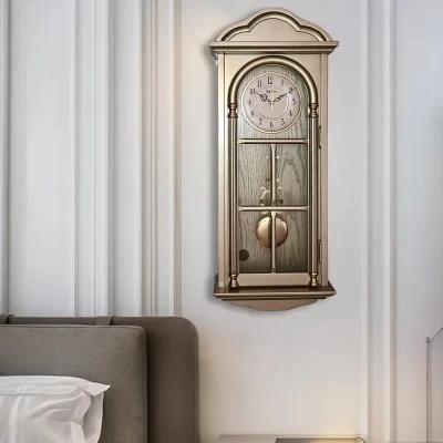 صورة لساعة حائط أنيقة بتصميم كلاسيكي مع بندول، مصنوعة من الخشب باللون العسلي وتحتوي على تفاصيل ذهبية.