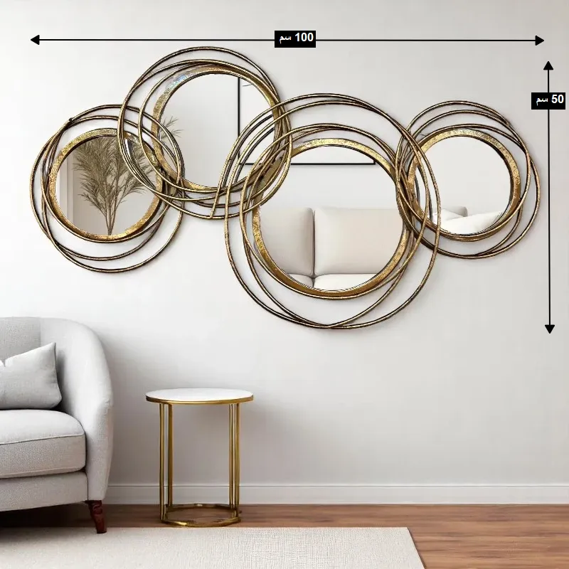 مرآة حائط معدنية ذهبية بتصميم عصري متداخل، موديل 029542 أبعاد اللوحة الجدارية المعدنية الذهبية المزودة بالمرايا، حيث يبلغ العرض 100 سم والارتفاع 50 سم.