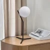 أباجورة عصرية، كرة زجاجية بيضاء، هيكل معدني أسود، إضاءة دافئة، تصميم أنيق، ديكور منزلي