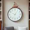 ساعة حائط عصرية بإطار بني داكن وتصميم غزال ذهبي، مناسبة لغرفة المعيشة أو المكتب.