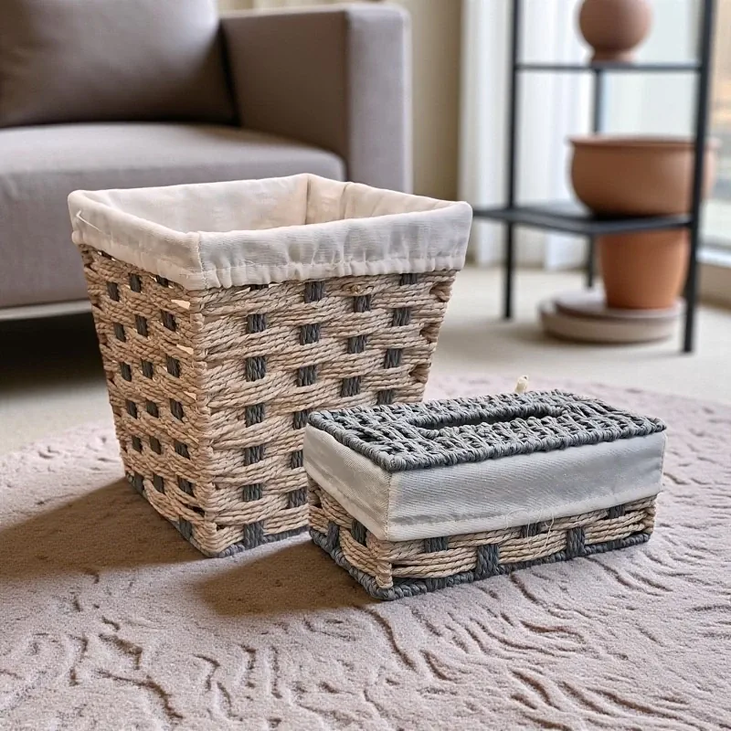 طقم سلة مهملات وعلبة مناديل بتصميم أنيق من الخوص والقماش، موديل 030138 صورة لطقم سلة مهملات وعلبة مناديل يدوية الصنع من الخوص والقماش، بتصميم غزل العيون، موضوعة على سجادة في غرفة معيشة عصرية.