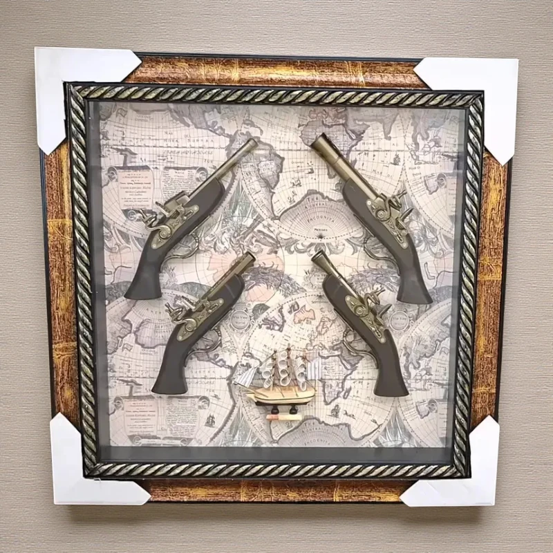 إخوان سرور الإضاءة الحديثة والديكور لوحة حائط ديكور مربع بإطار ذهبي وبني، تحتوي على 4 مسدسات عتيقة ومجسم سفينة شراعية على خلفية خريطة عالم قديمة.