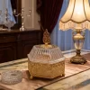 بونبونيرة ذهبية سداسية معدنية مع وعاء من السيراميك مع غطاء أكريليك مضلع يعلوه مقبص فوق طاولة ضيافة فاخرة.